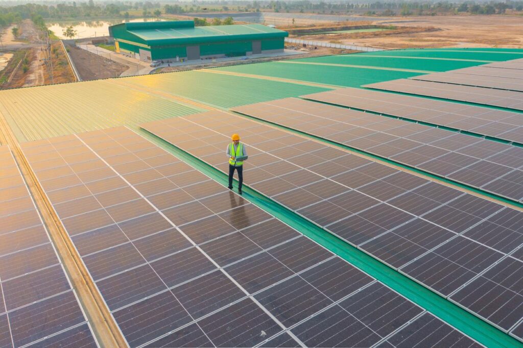 Aerial view of solar worker near solar panels on the roof of a business.