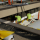 Two Men In Bright Green Shirts With Company Branding Working On Roof